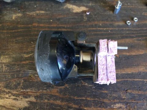 2002 Pontiac Grand Prix - A close-up view of a modified headlight assembly, possibly for a 2002 Pontiac Grand Prix, is mounted on a wooden surface. The assembly feat…