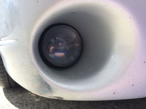 2002 Pontiac Grand Prix - A close-up view of the driver's side fog light on a silver 2002 Pontiac Grand Prix. The bumper shows some scuffing and wear.