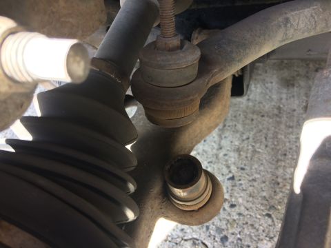 2002 Pontiac Grand Prix - This close-up image shows a heavily rusted suspension component, likely a sway bar end link, on a vehicle. The rubber boot is torn, and the…