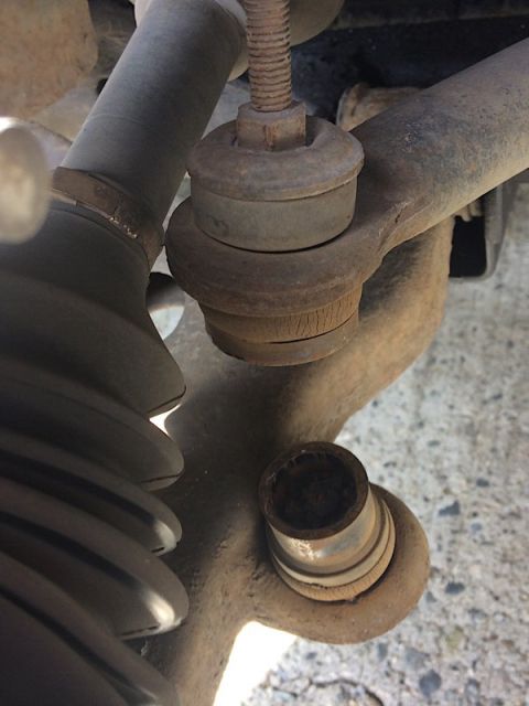 2002 Pontiac Grand Prix - A close-up view of heavily rusted suspension components on a vehicle, including a ball joint with cracked rubber boots and a tie rod end.