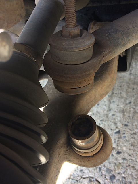 2002 Pontiac Grand Prix - This close-up image shows a heavily rusted automotive suspension component, likely a ball joint, with a torn rubber boot visible on the lef…