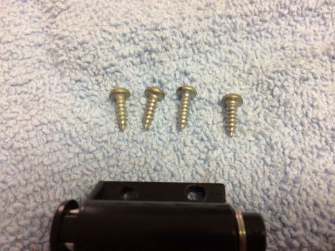 2002 Pontiac Grand Prix - Four screws are laid out on a light blue textured surface, with a black automotive part visible in the foreground.