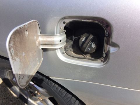 2002 Pontiac Grand Prix - The image shows a close-up of an open fuel filler door on a silver car, revealing the gas cap and surrounding area. The fuel door and the a…