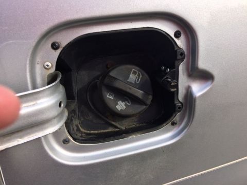 2002 Pontiac Grand Prix - A close-up view of the fuel filler door of a silver vehicle, showing the gas cap and the mechanism for the door.
