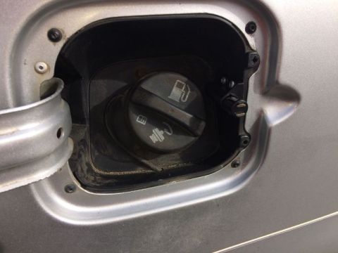 2002 Pontiac Grand Prix - A close-up view of a silver car's fuel filler door, showing the gas cap and surrounding metal trim. The gas cap has symbols for fuel and em…