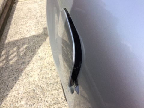 2002 Pontiac Grand Prix - A close-up side view of the fuel door on a silver car. The fuel door is slightly ajar, revealing some of the inner workings.
