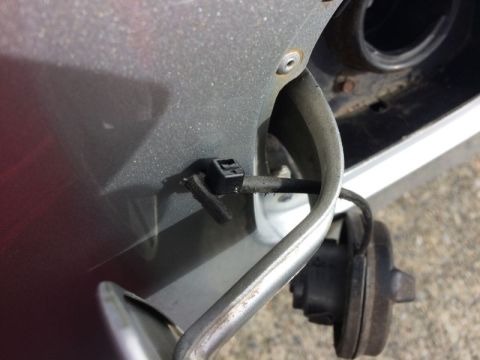 2002 Pontiac Grand Prix - A close-up view shows the fuel filler neck and cap assembly on a vehicle, with a black plastic clip securing a wire to the body panel.