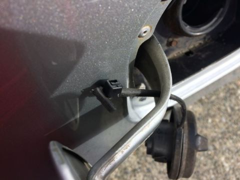 2002 Pontiac Grand Prix - A close-up view shows a broken fuel door tether on a gray car. The tether is detached from its clip and hangs loosely, with the fuel cap vi…
