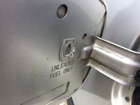 2002 Pontiac Grand Prix - A close-up shot of the "UNLEADED FUEL ONLY" text and a clear plastic cap on the fuel door of a silver vehicle.