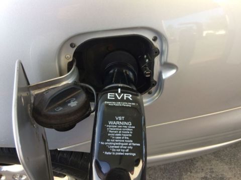 2002 Pontiac Grand Prix - A close-up view of a silver car's fuel filler neck with a black fuel nozzle inserted. The nozzle has text that includes "EVR" and "WARNING"…