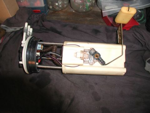 2002 Pontiac Grand Prix - A disassembled fuel pump assembly with a fuel level sender is shown resting on a dark cloth. The assembly includes a white plastic housing,…