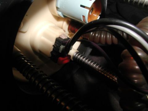 2002 Pontiac Grand Prix - A close-up view shows a white plastic fuel pump housing with a black electrical connector and a red release tab. Several ribbed hoses and c…