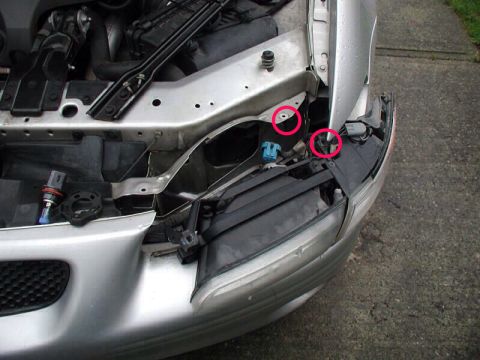 2002 Pontiac Grand Prix - Close-up view of the front fender and headlight assembly of a silver car, showing some of the internal components and mounting points.