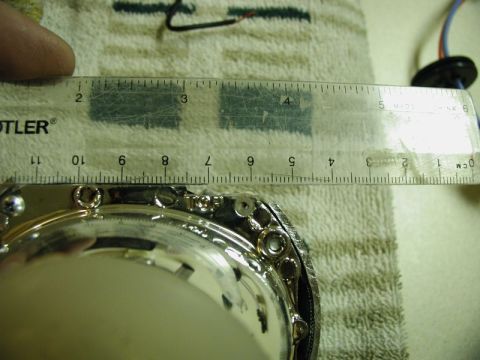2002 Pontiac Grand Prix - A close-up view shows a ruler measuring a part of a vehicle's headlight assembly. The ruler is placed over the chrome bezel and mounting sc…