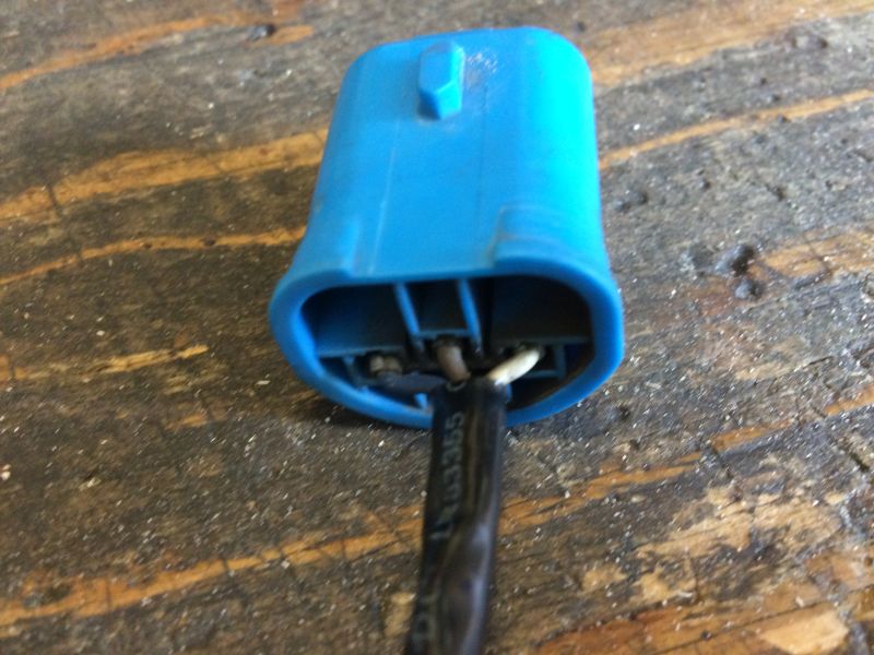 Blue electrical connector with wires on a wooden surface.