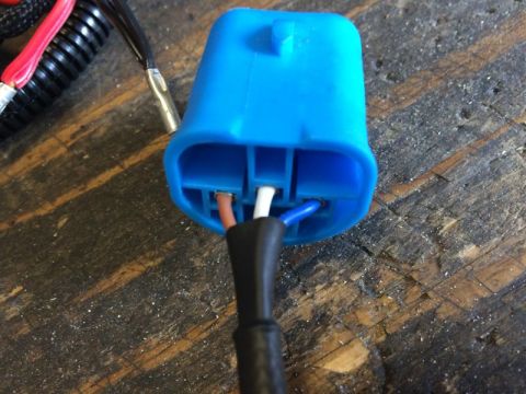 2002 Pontiac Grand Prix - A close-up shot shows a blue electrical connector with three wires: brown, white, and blue, emerging from a black cable. The connector is p…