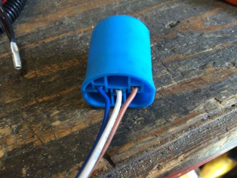 2002 Pontiac Grand Prix - A blue electrical connector with three wires (blue, white, and brown) protruding from it rests on a weathered wooden surface. A separate bl…
