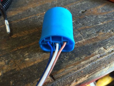 2002 Pontiac Grand Prix - A blue plastic electrical connector housing with three wires (white, brown, and blue) protruding from it sits on a weathered wooden surface.