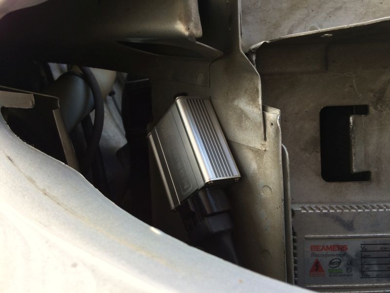 Silver ballast with fins and black connector mounted on vehicle frame. Text "BEAMERS" visible.