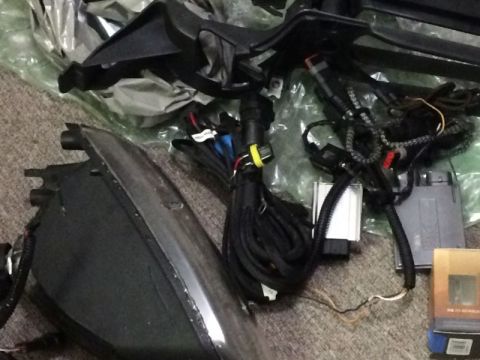 2002 Pontiac Grand Prix - A collection of car parts, including a headlight assembly, wiring harnesses, and electronic modules, are laid out on a carpeted surface.