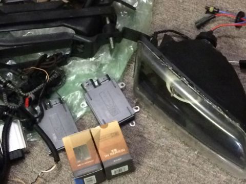 2002 Pontiac Grand Prix - A collection of automotive lighting parts, including headlights, ballasts, and wiring harnesses, are laid out on a carpeted surface.