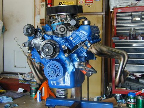 1979 Ford Bronco - A freshly painted blue Ford V8 engine mounted on a stand in a garage, fitted with an Edelbrock intake and carburetor, chrome pulleys and tu…