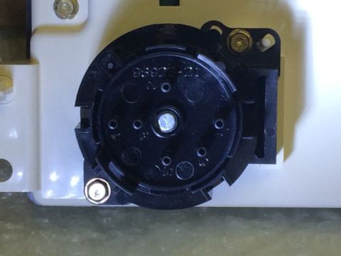 2002 Pontiac Grand Prix - A close-up, overhead view of a black rotary switch mechanism, likely part of a vehicle's dashboard or control panel, mounted on a white pla…