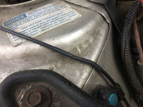 2002 Pontiac Grand Prix - A close-up view of a black wire with heat shrink tubing over a splice, running across a metal surface with a warning sticker. The sticker i…