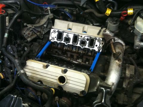 2002 Pontiac Grand Prix - The image shows a close-up view of a car engine with the intake manifold removed, revealing the camshafts and valves. Blue spacers are visi…