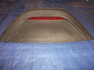2002 Pontiac Grand Prix - A black, aftermarket rear spoiler with a red reflector is shown mounted on a blue tarp. The spoiler has a wide, curved shape and appears to…