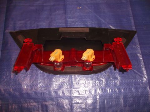 2002 Pontiac Grand Prix - A close-up view of a red and black automotive part, likely a taillight assembly, with two yellow electrical connectors visible.