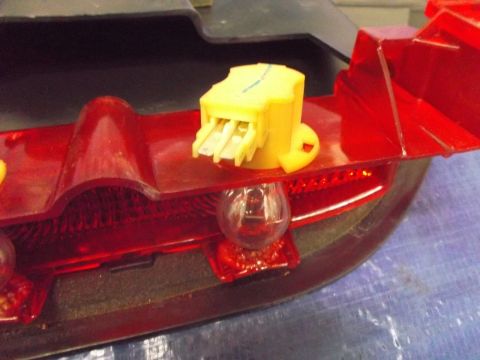 2002 Pontiac Grand Prix - A close-up view shows the internal components of a red taillight assembly, including a clear bulb and a yellow electrical connector with me…