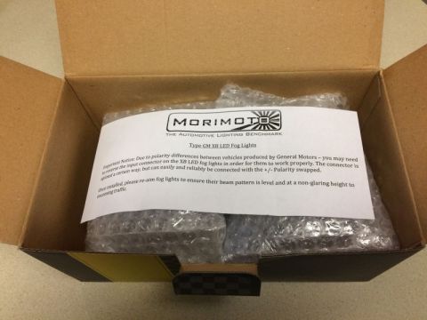 2002 Pontiac Grand Prix - An open cardboard box containing a set of Morimoto XB LED Fog Lights for GM vehicles. The included instruction sheet details polarity diffe…