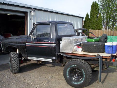 1978 Ford Bronco - This pickup truck, likely from the 1970s, has been modified with a flatbed and is parked outside a garage.