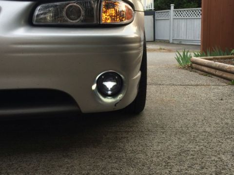 2002 Pontiac Grand Prix - A close-up, low-angle shot of the front bumper and headlight of a silver Pontiac Grand Prix. The driver's side fog light is illuminated, sh…