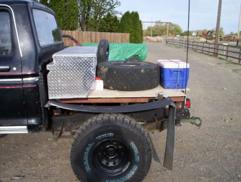 1978 Ford Bronco - The rear of a truck bed is shown, loaded with a spare tire, a blue cooler, and a diamond plate toolbox.