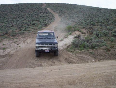 1978 Ford Bronco - 1978 Ford Bronco navigating an off-road trail on a dry, hilly landscape.