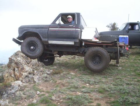 1978 Ford Bronco - A man drives a modified pickup truck over rocky terrain, with another truck visible in the background.