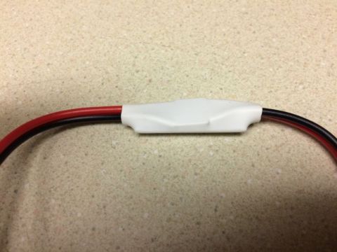2002 Pontiac Grand Prix - A close-up shot shows a white plastic casing covering a splice in a red and black wire. The wires are curved and resting on a speckled coun…