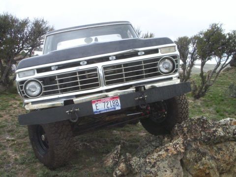 1978 Ford Bronco - This Ford truck is navigating a rocky terrain with its front grille and headlights clearly visible.