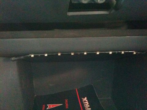 2002 Pontiac Grand Prix - A close-up view of a car's interior, possibly a glove compartment, showing an LED light strip installed along the top edge. A portion of a…