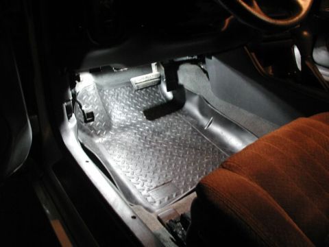 2002 Pontiac Grand Prix - The interior of a vehicle shows a black diamond plate floor mat on the driver's side, covering the carpet. The brake and gas pedals are vis…