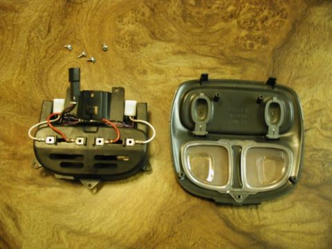 2002 Pontiac Grand Prix - Two disassembled parts of a vehicle's interior light fixture are laid out on a wood-grain surface. The left part shows wiring and switches,…