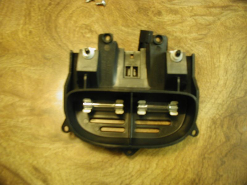 Black plastic automotive fuse box with two glass fuses installed
