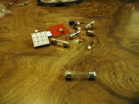 2002 Pontiac Grand Prix - A collection of small electronic components, including LED light panels, incandescent bulbs with wires, and fuses, are laid out on a wood-g…