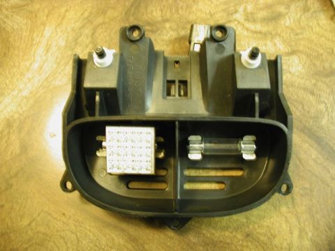 2002 Pontiac Grand Prix - A black plastic automotive fuse box assembly with two fuses visible. One fuse is a glass tube type, and the other is a block of smaller fus…
