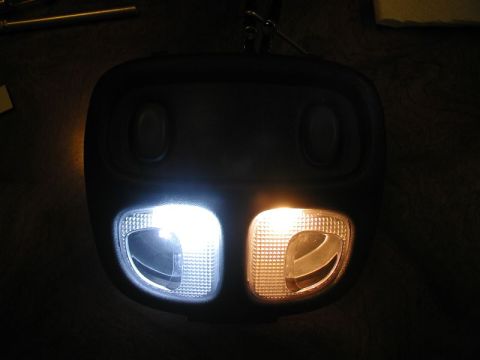 2002 Pontiac Grand Prix - A close-up shot of a vehicle's interior overhead console with two lights. The left light emits a bright white light, while the right light…