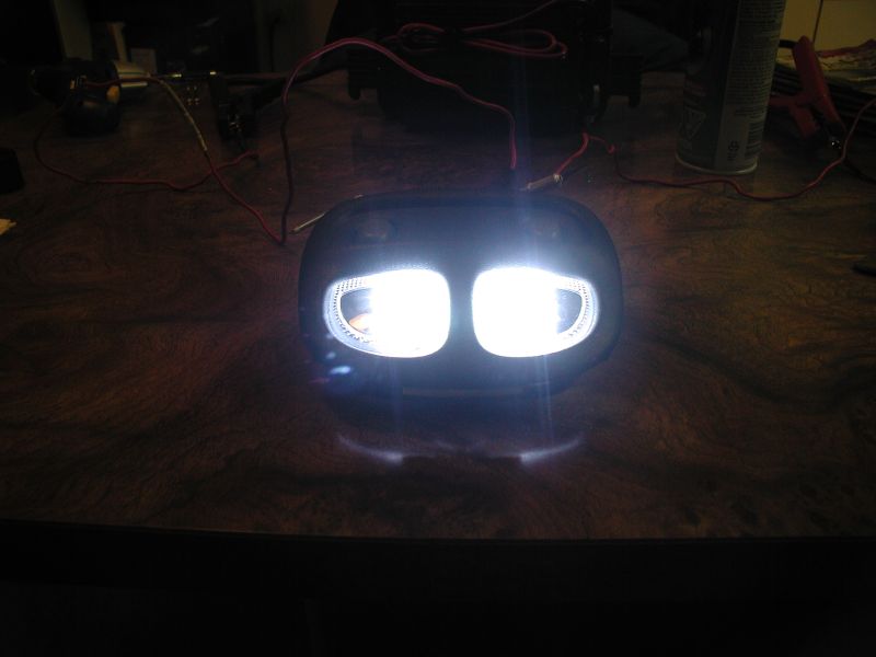 Illuminated LED headlights on a wooden surface, wired for a project.