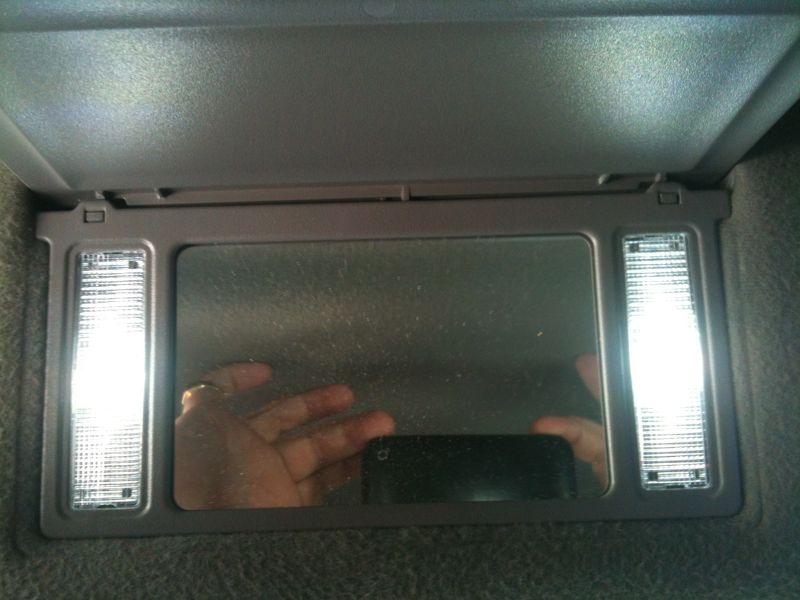 Car visor mirror with illuminated vanity lights.