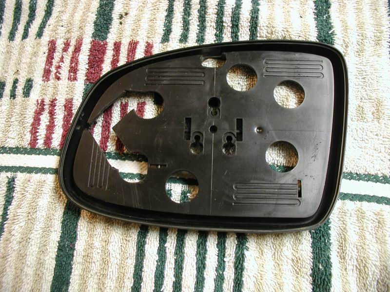 Black plastic side mirror housing with circular cutouts on a striped towel.